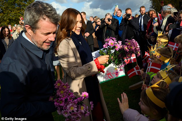 Королева Мария и король Фредерик приветствовали королевских поклонников, размахивающих датскими флагами. Оба члена королевской семьи получили букеты розовых цветов, а Мэри подписала открытку.